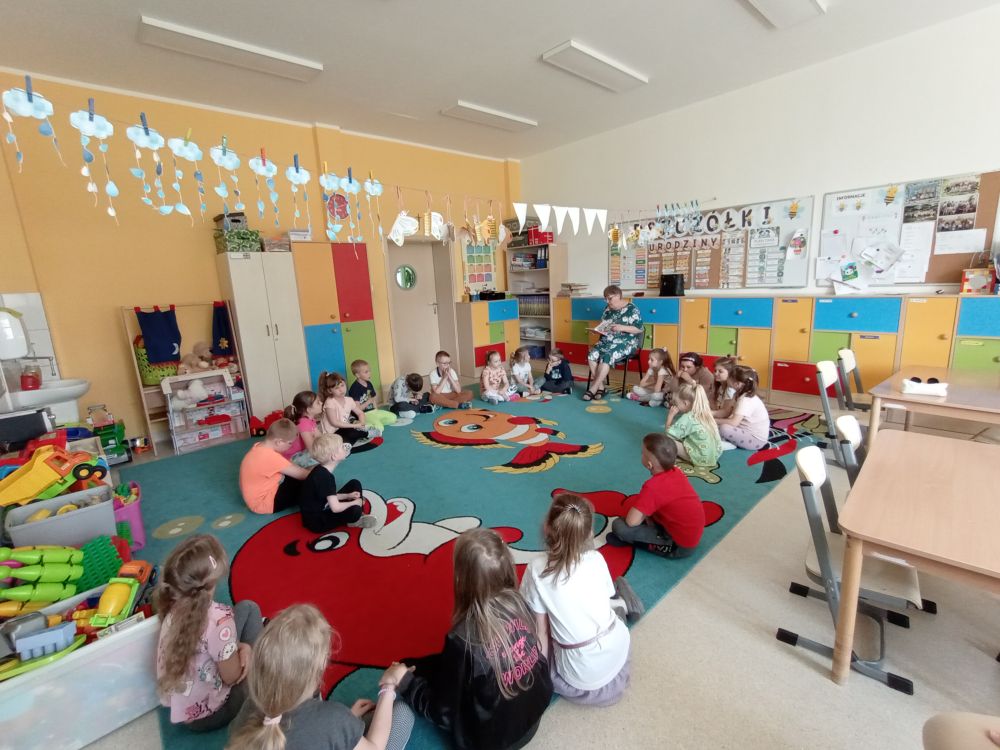 Uczestniczka Klubu Seniora czyta dzieciom książkę w Przedszkolu Leśna Kraina